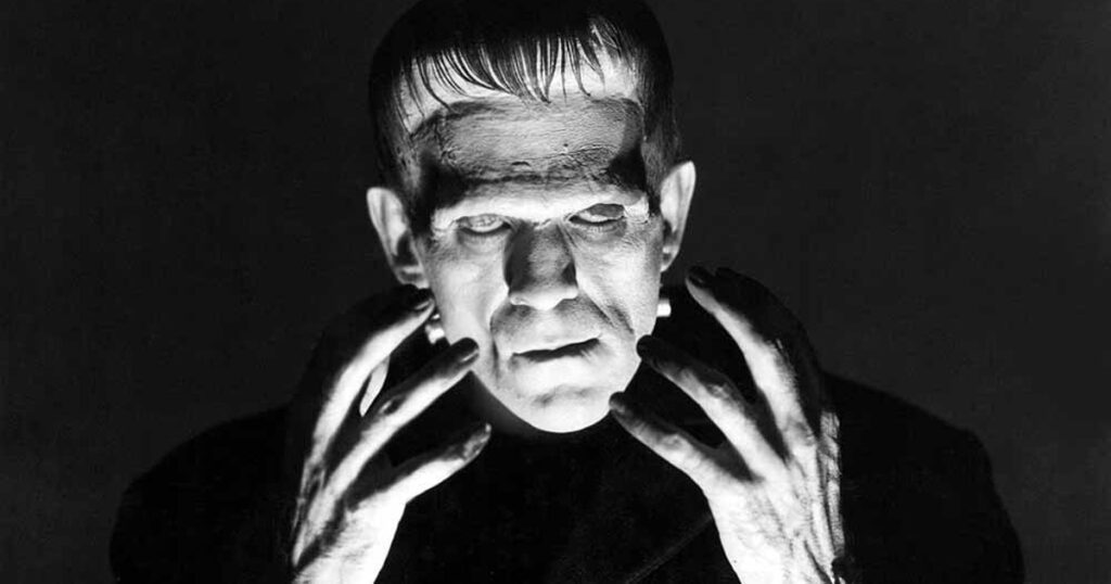 Il primo vero mostro della storia dei film horror, Frankenstein, inquadrato in primo piano mentre ha le mani verso il volto 